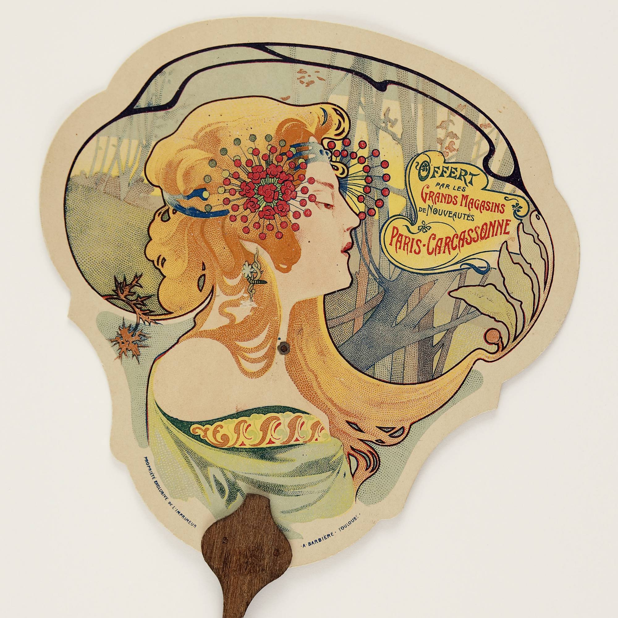 fan with lithographic print of woman with flowers in her long, orange hair next to text that reads "Grands Magasins de Nouveautes"